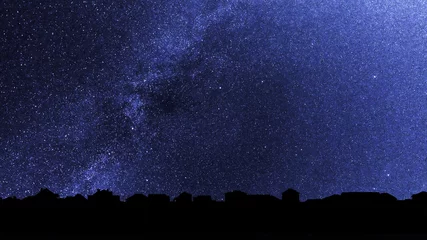 Tragetasche Sternenhimmel über den Dächern der Vorstadthäuser. Hintergrund mit Millionen von Sternen über dem Dorf. Dunkle Skyline im Gegenlicht. © nskyr2
