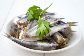 bunch of raw sardines on plate with parsley
