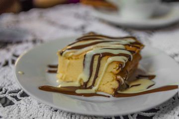 Slice of delicious cake on white plate on table