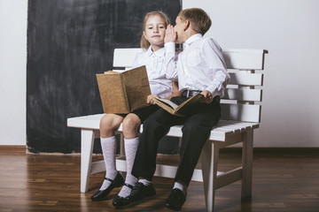 Boy and girl from primary school class on the bench read books o