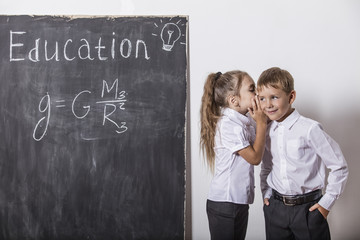 Boy and girl of elementary school in class background slate