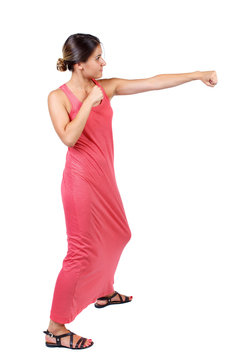 skinny woman funny fights waving his arms and legs. Isolated over white background. A slender woman in a long red dress fulfills hands.