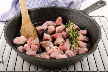 roasted bacon cubes with rosemary in a cast iron pan