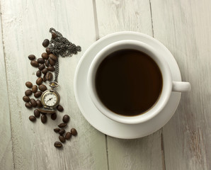 Cup of black coffee with coffee beans and vintage watch