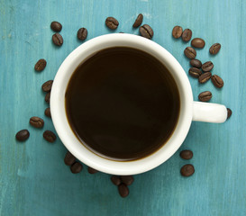 Сup of coffee with coffee beans on vibrant turquoise background
