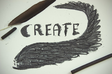 Word Create and black wing drawn by art charcoal.