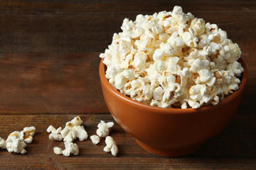 A bunch of popcorn in bowl on a brown wooden background