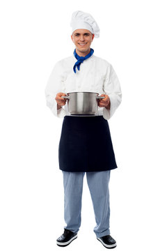 Smiling chef holding vessel and posing.