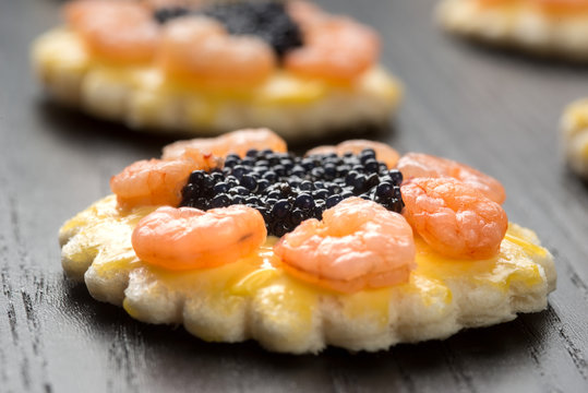 Tartine rotonde con code di gamberetti e uova di lompo