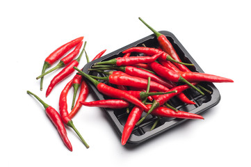 Heap of red hot chili pepper in black container on white backgro