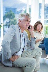 Smiling man by woman talking on mobile phone