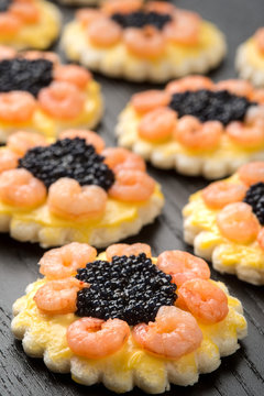 Tartine rotonde con code di gamberetti e uova di lompo