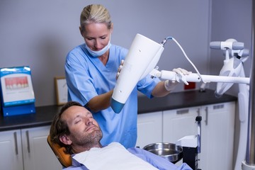 Dentist assistant adjusting light over patients mouth