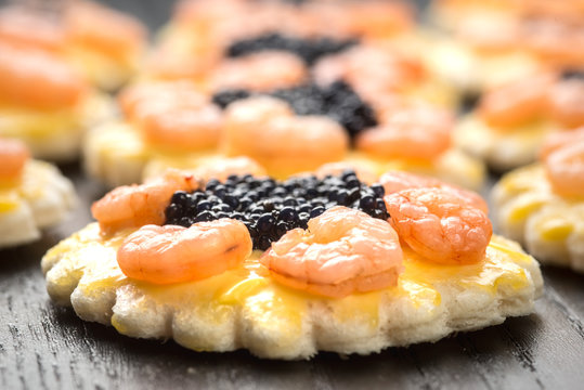 Tartine rotonde con code di gamberetti e uova di lompo