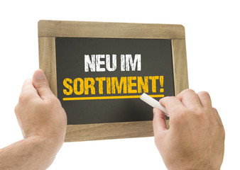 Hand schreibt neu im Sortiment! auf Kreidetafel