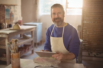 Portrait of male potter using digital tablet