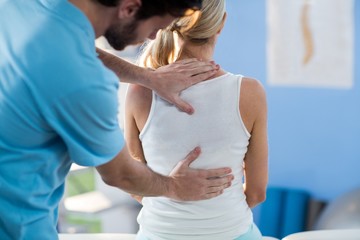 Male physiotherapist giving back massage to female patient - obrazy, fototapety, plakaty