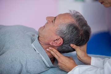 Senior man receiving neck massage from physiotherapist