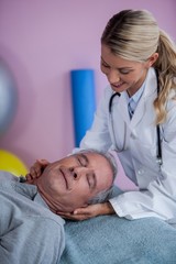 Obraz na płótnie Canvas Senior man receiving neck massage from physiotherapist