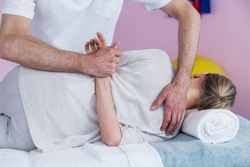 Obraz na płótnie Canvas Physiotherapist massaging a senior womans shoulder 