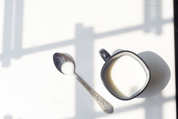 black cup of milk and spoon on natural white background, top view