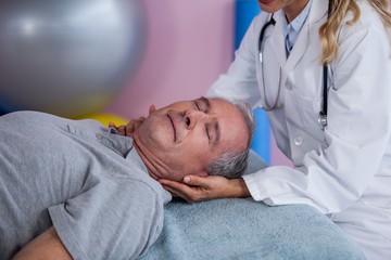 Obraz na płótnie Canvas Senior man receiving neck massage from physiotherapist