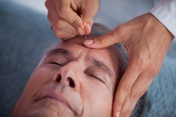 Senior man receiving head massage from physiotherapist - obrazy, fototapety, plakaty