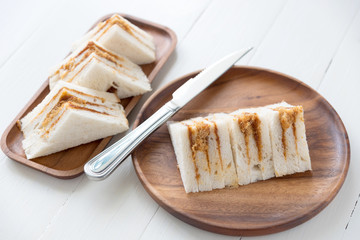 finger sandwiches triangles in wooden plate on white table
