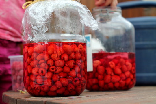 Sappy ripe raspberries in glass pots spilled with juice