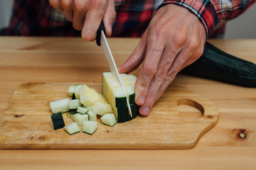 Man hands slicing fresh zucchini by ceramic knife