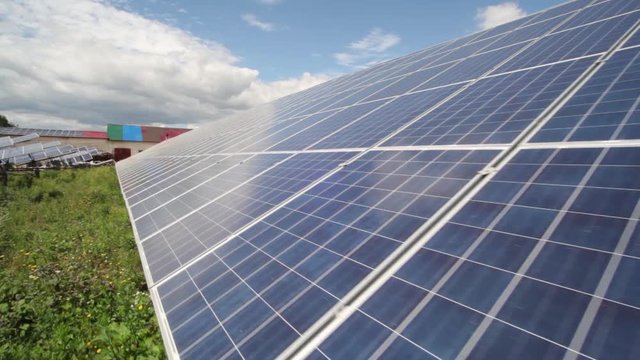 Solar panels used to generate electricity from sunlight against clouds and sky.