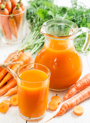 Carrot juice and fresh carrots on wooden background