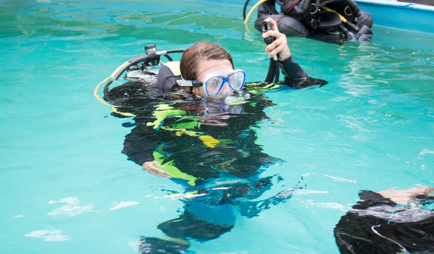 Young girl doing a scuba diving training in an outdoor pool with diving equipment mask and snorkel