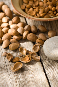 Bowl of almonds (Prunus dulcis) broken and in nutshells on table