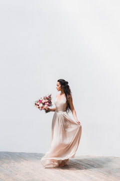 The bride with a huge bouquet of peonies and roses on a white ba