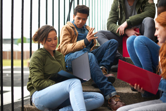 Young adult college student friends revising on campus stairs