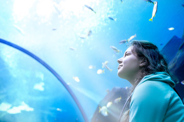 Young pretty woman watching fishes in a tropical aquarium