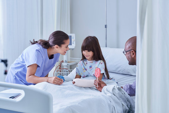 Doctor and nurse offering girl patient lollipops in hospital children's ward