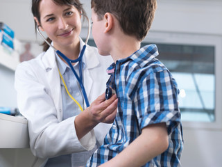 Doctor checking boy's breathing with stethoscope