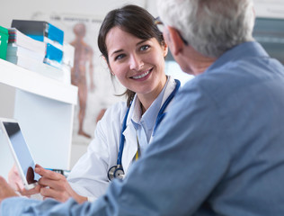 Doctor sharing health information on digital tablet with patient in clinic