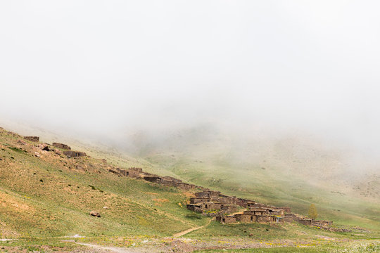 Misty landscape view of stone houses on hillside, Oukaimeden ski resort, Marrakech, Morocco