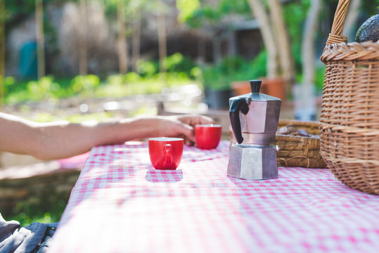 Man's hand with espresso cup at table in garden
