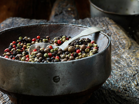 All spice in vintage bowl, rustic wooden chopping board