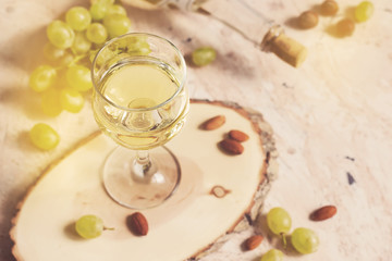 Glass of white wine on the background of grapes and nuts, tinted