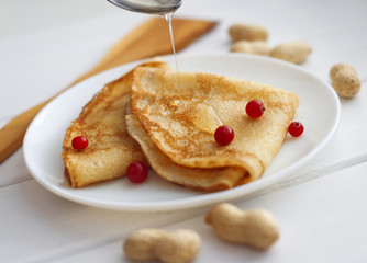 Tasty pancakes with honey and cranberry on white table