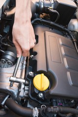 Hand repairing a modern car engine with a wrench