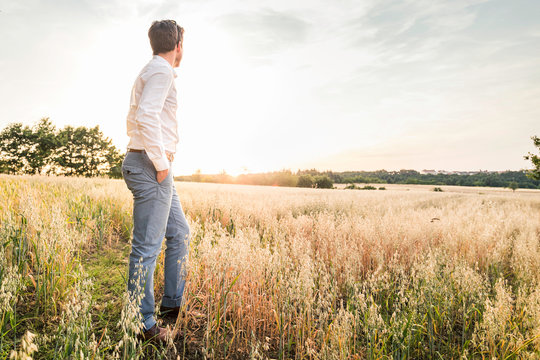 Smart young man looking across field, Kirchheimbolanden, Rheinland-Pfalz, Germany
