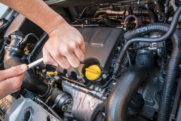 Hands repairing a modern car engine with a wrench