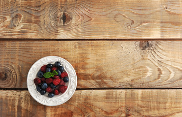 Fototapeta na wymiar blueberries and raspberries with mint in bowl