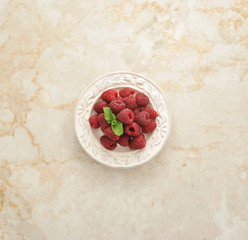 fresh raspberries on a plate on a marble background